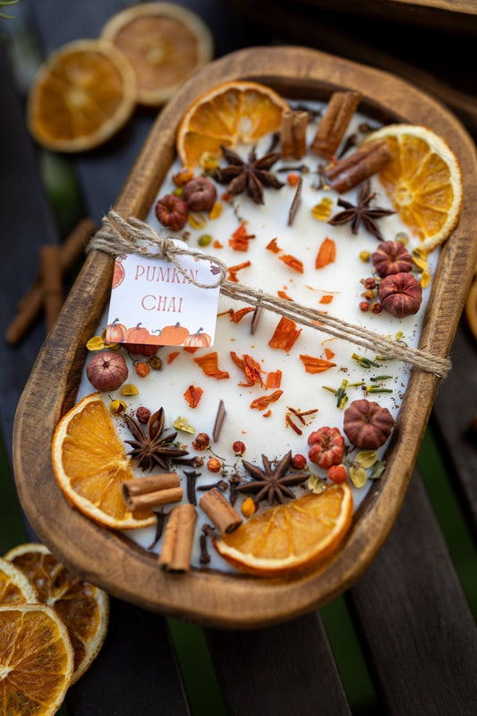 Wooden bowl candle with white wax, dried orange slices, cinnamon sticks, and spices