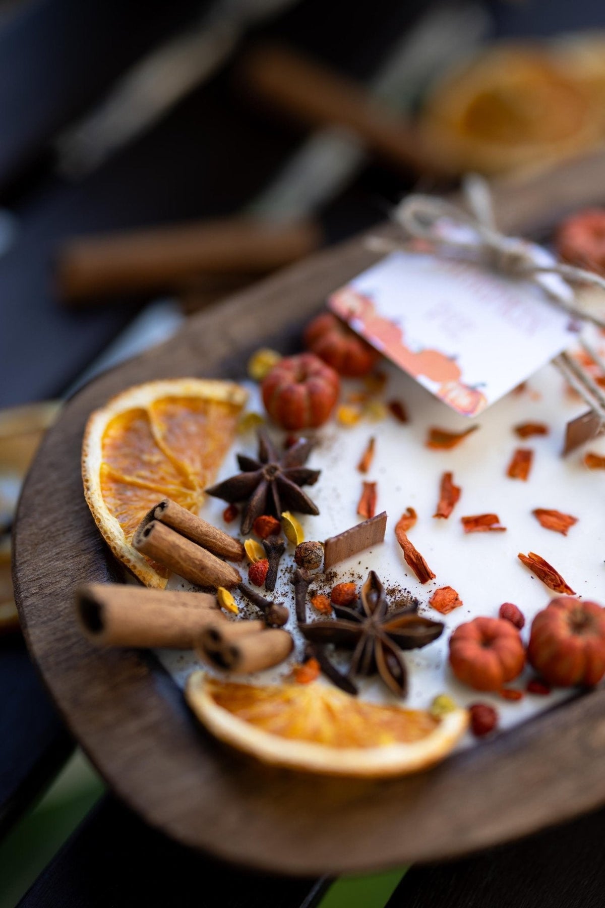 Large wooden candle bowl close-up with cinnamon sticks, star anise, and dried citrus slices