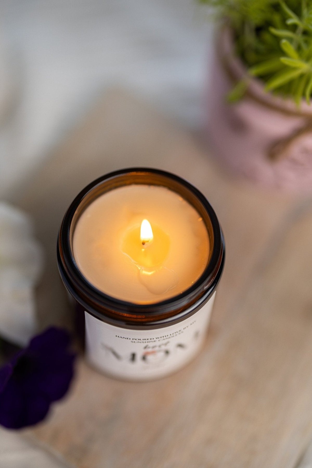 Amber jar candle with lit wick, top view showing flame inside the jar.