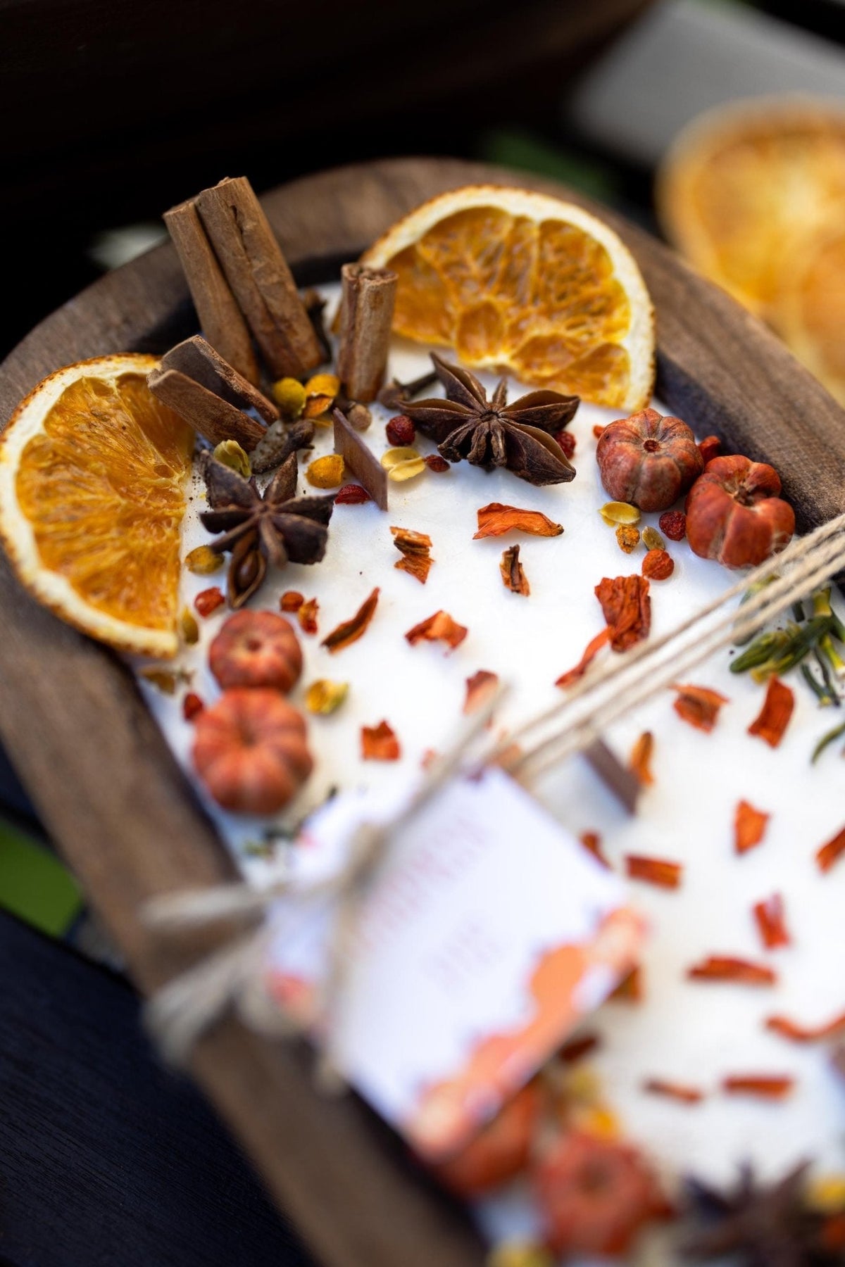 Large wooden candle bowl angled view with orange slices, star anise, cinnamon sticks, wax