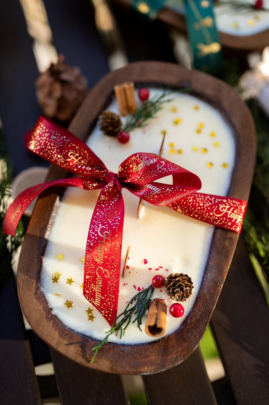Handcrafted wooden dough bowl candle with red ribbon bow and holiday botanicals