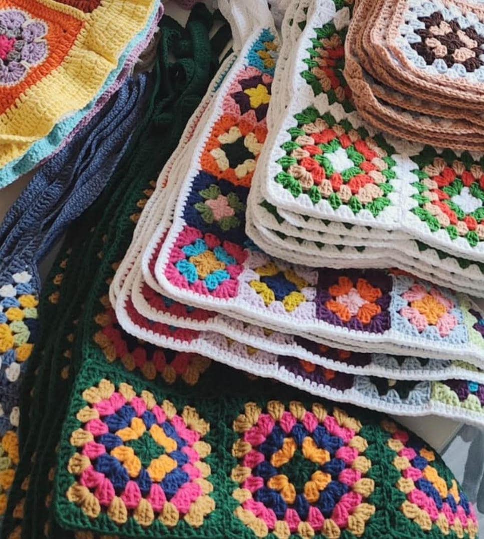 Stack of colorful crochet granny square bandanas with multi-color flower motifs