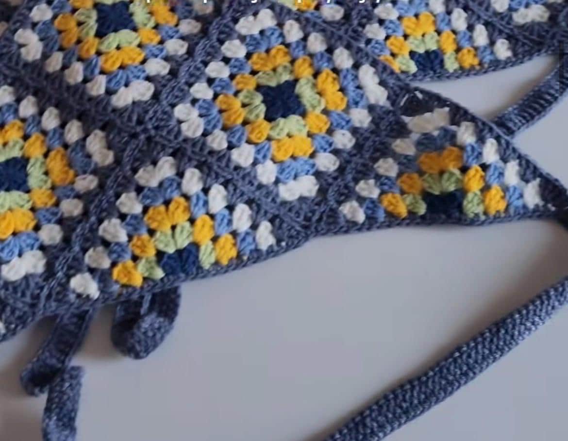 Blue crochet bandana with yellow and white granny square texture and tied ends