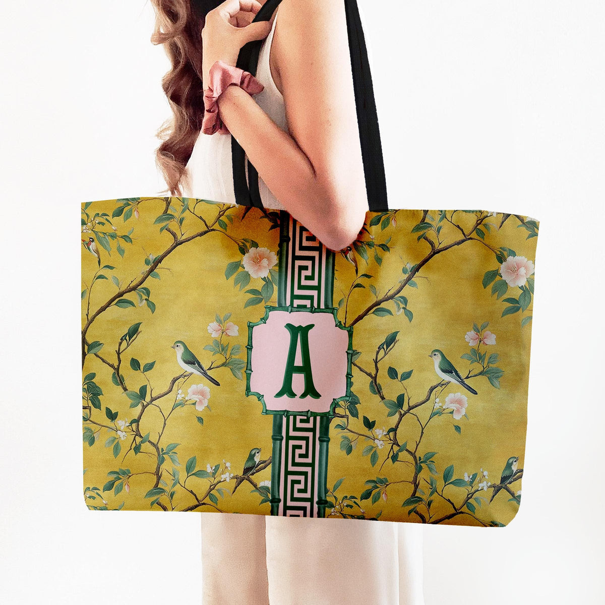 Yellow mahjong tote bag with black web handles, bird-and-floral print, and green monogram