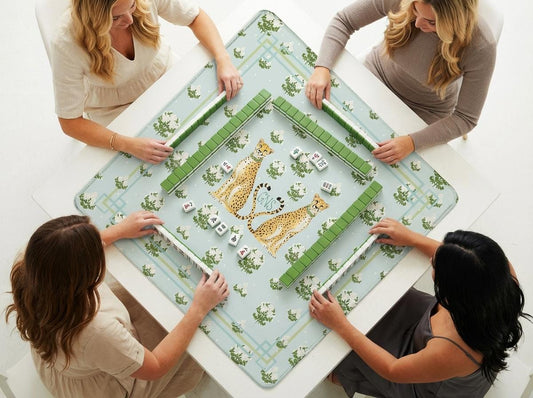 Custom mahjong mat with twin cheetahs and botanical print, shown beneath a mahjong game