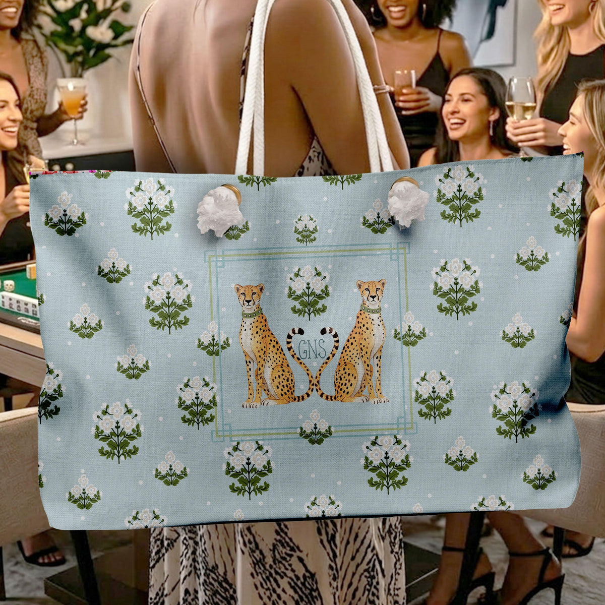 Personalized tote bag with white rope handles, blue floral print, and paired cheetah monogram design