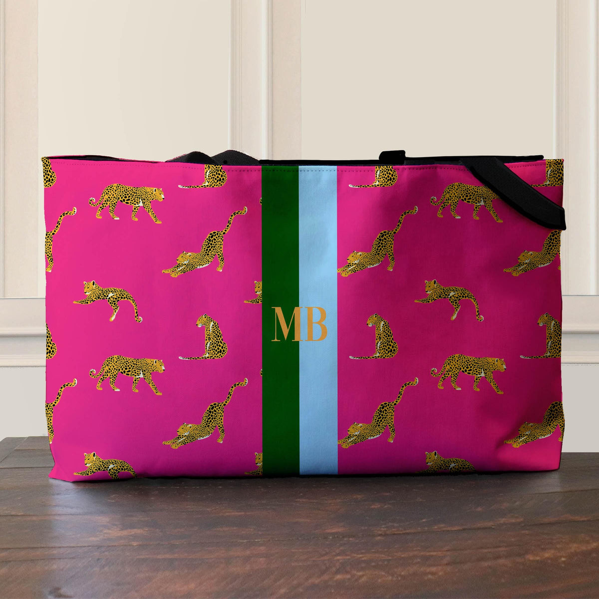 Pink leopard print tote with black web handles and a green and blue monogram stripe