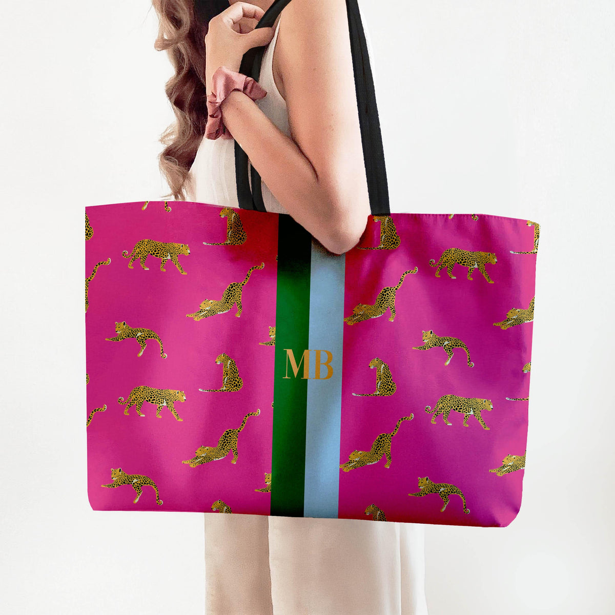 Pink leopard print tote with black web handles and a monogram stripe