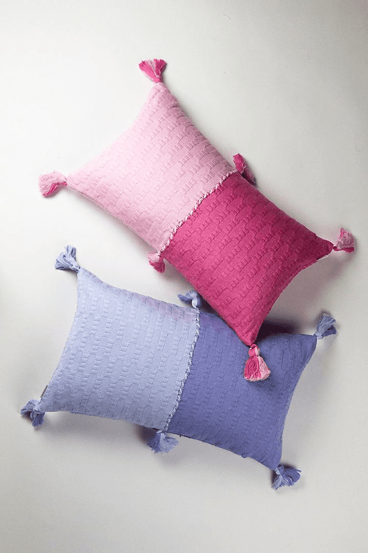 Colorblocked decorative pillows, pink and periwinkle blue, with tassel corners.