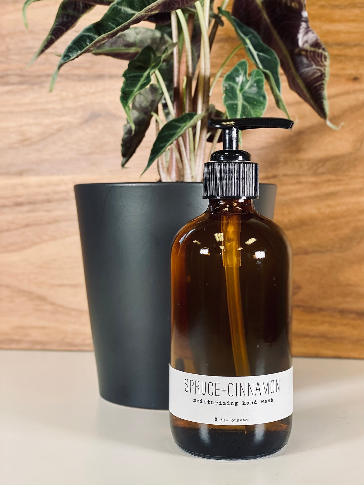 Amber hand wash bottle with black pump, spruce+cinnamon label