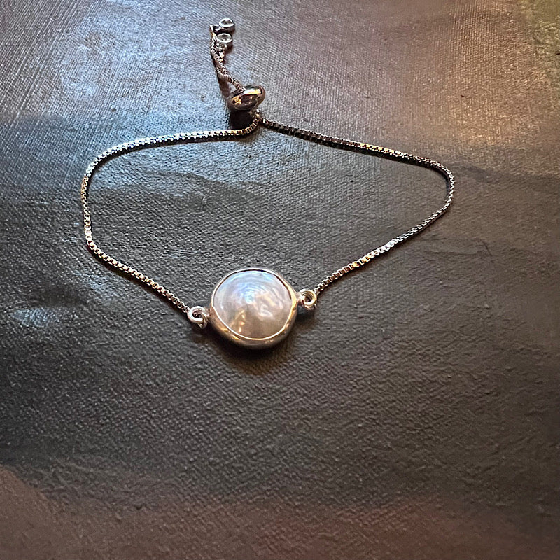 Adjustable silver-tone bracelet with round coin pearl pendant and small faith charm