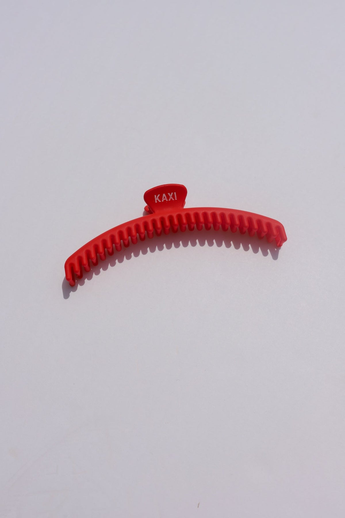 Red matte claw hair clip close-up with ridged grip