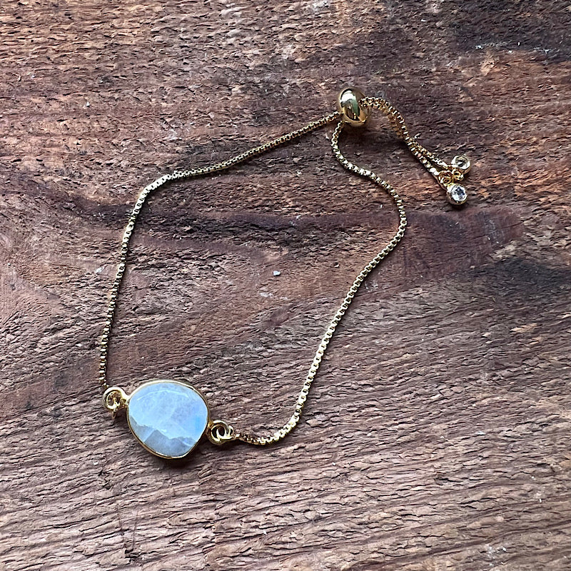 Gold-tone chain bracelet with large round blue moonstone centerpiece and blue charm