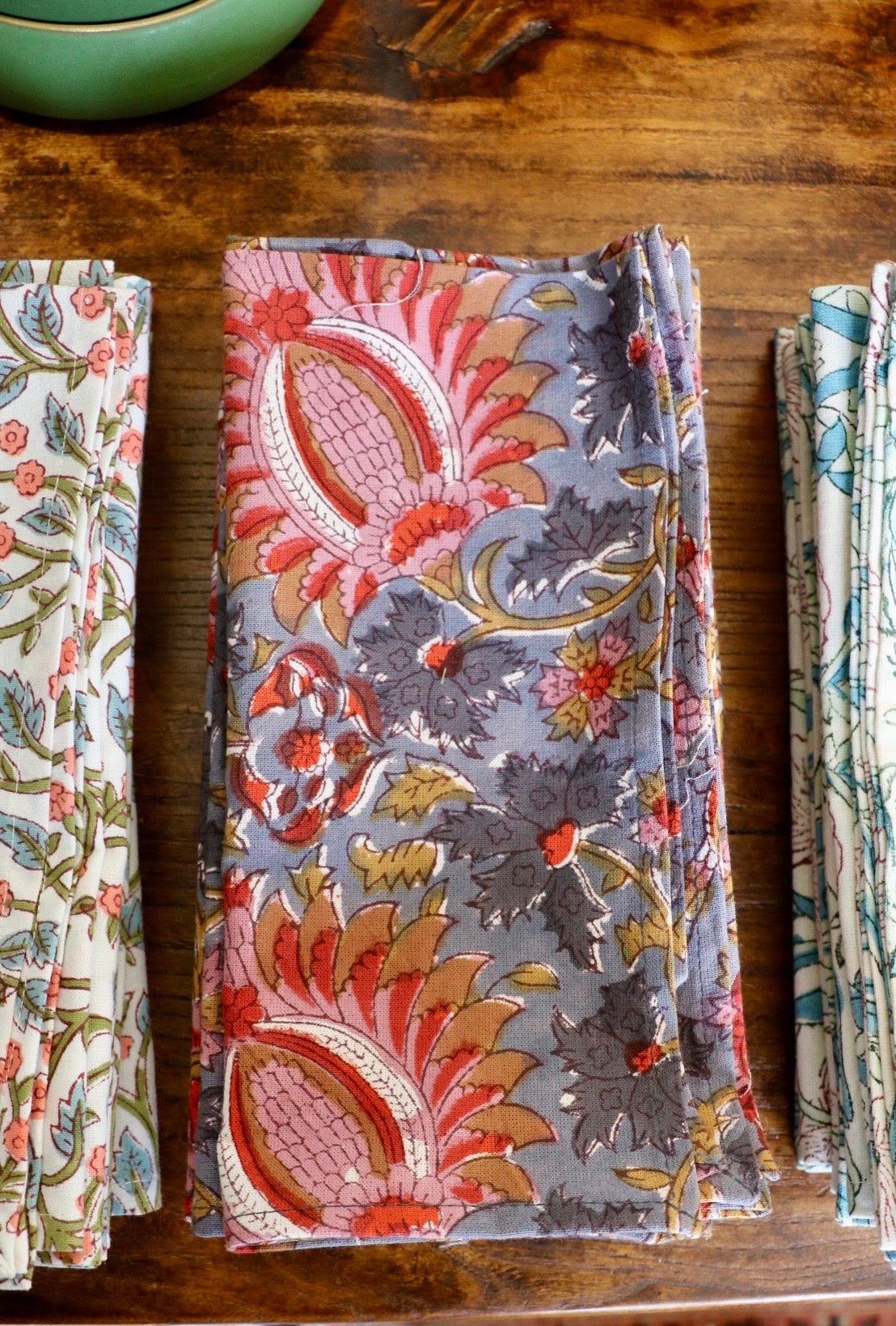 Botanical garden napkins in red, gray, and multicolor floral leaf pattern, folded rectangles