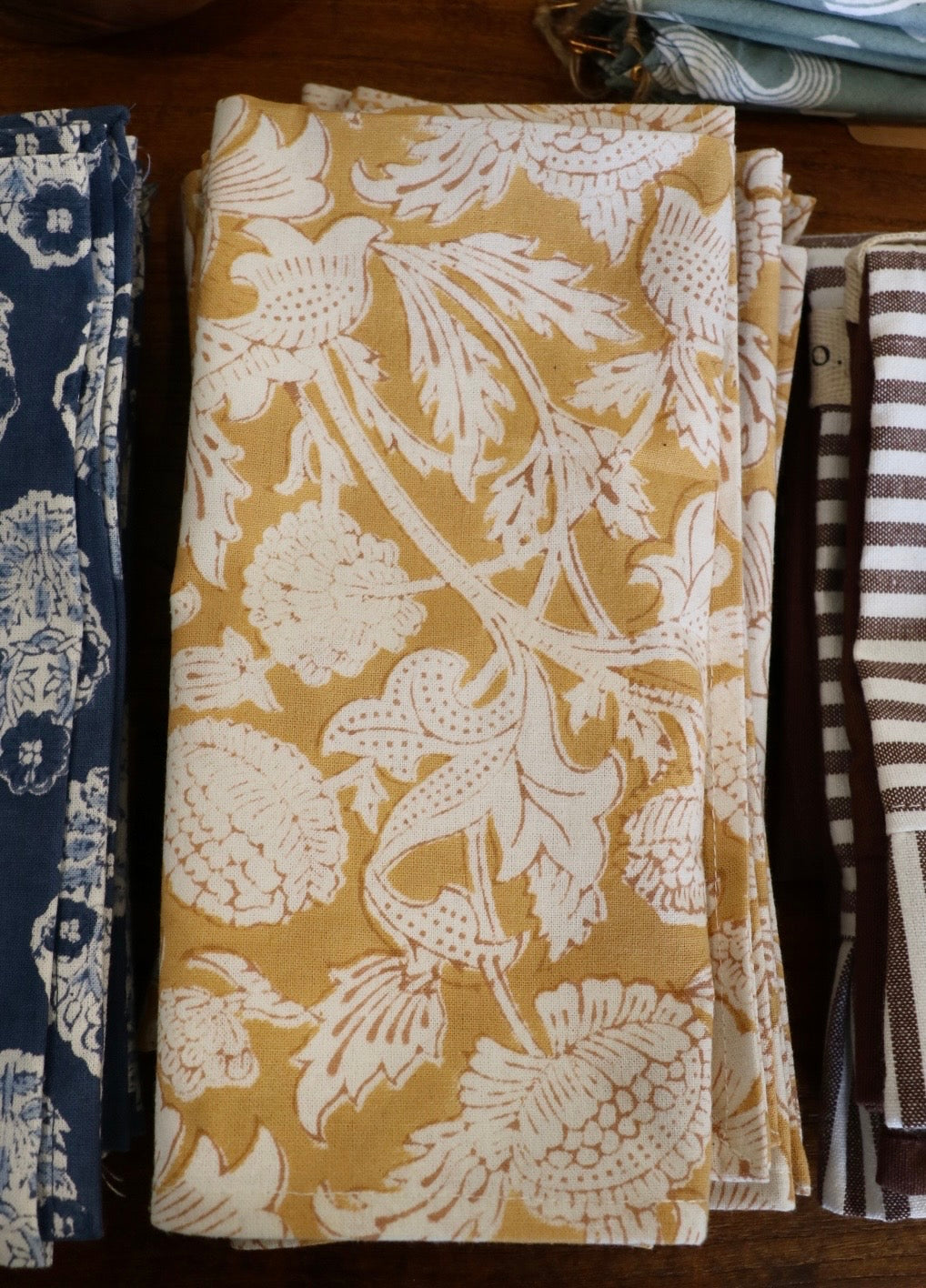 Botanical garden napkins in warm tan with gold botanical leaf and bird pattern, folded