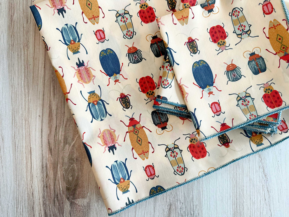 Set of four beetle-print cloth napkins with blue stitched border