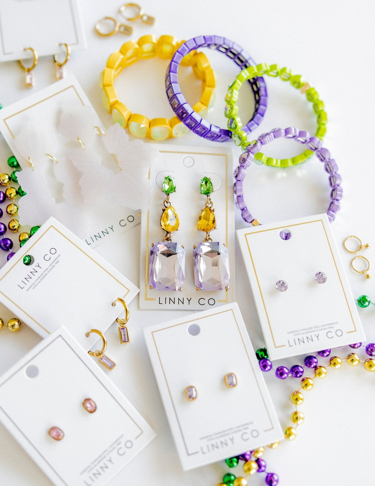 Gold-tone statement earrings with green tops, yellow charms, and purple faceted drops
