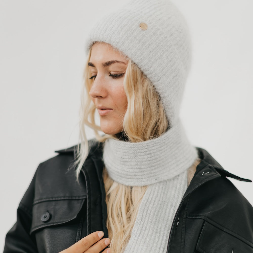 Light gray ribbed knit beanie with matching scarf wrapped closely around the neck