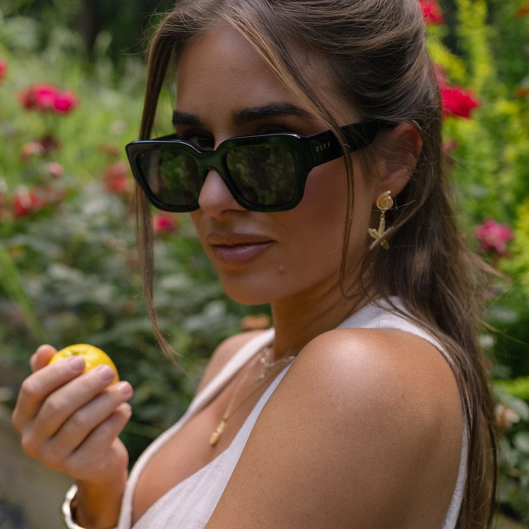 Polarized sunglasses with black frames and dark gray lenses on a woman outdoors