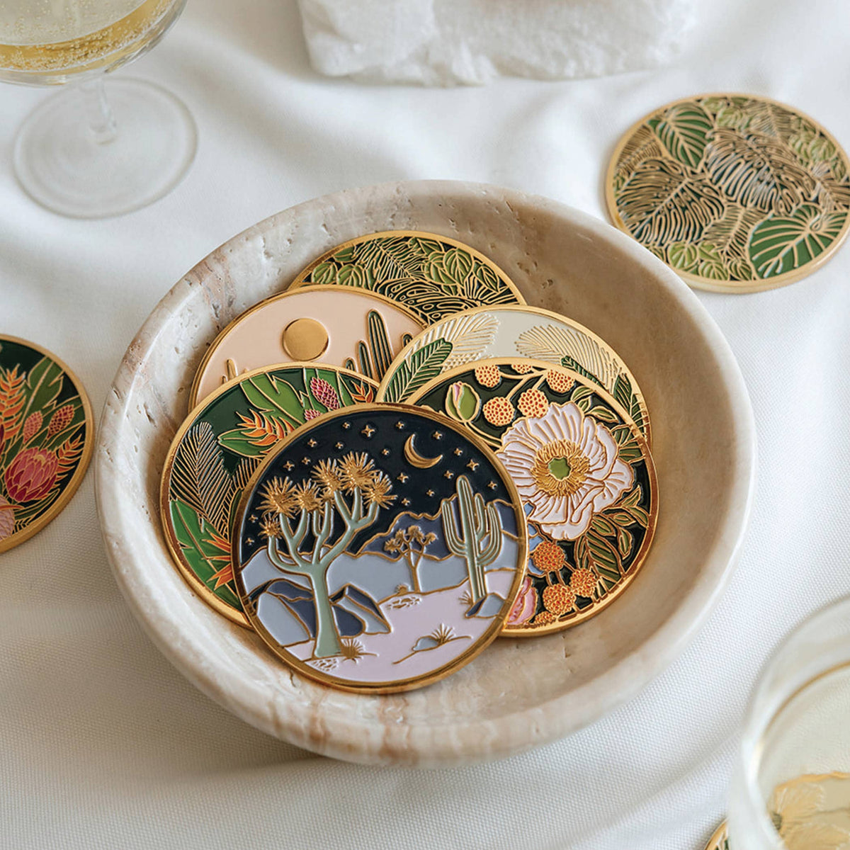 Round coaster with gold rim, dark desert scene with flowers, stars, and moon