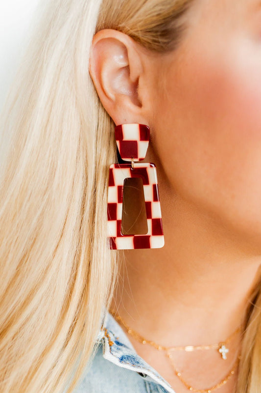 Geometric maroon-and-cream checkered dangle earrings on ear, rectangular shapes