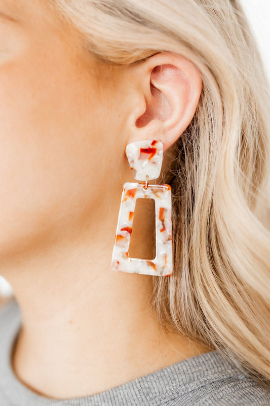 Large rectangle statement earrings in white resin with orange speckles, worn