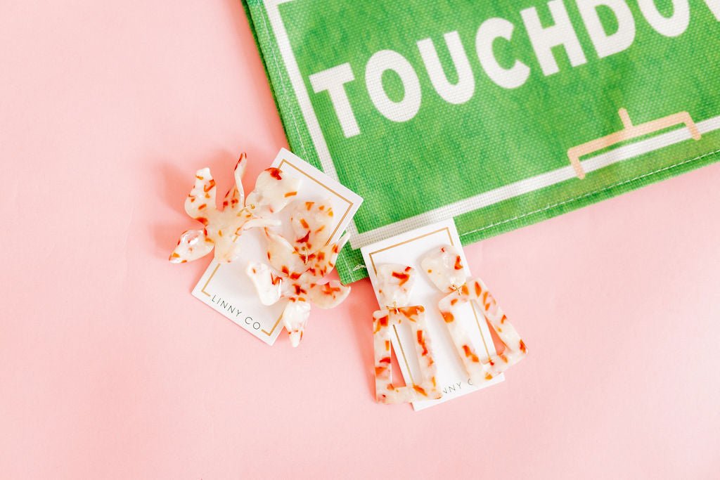 Orange-and-white speckled resin rectangle earrings shown on a display card