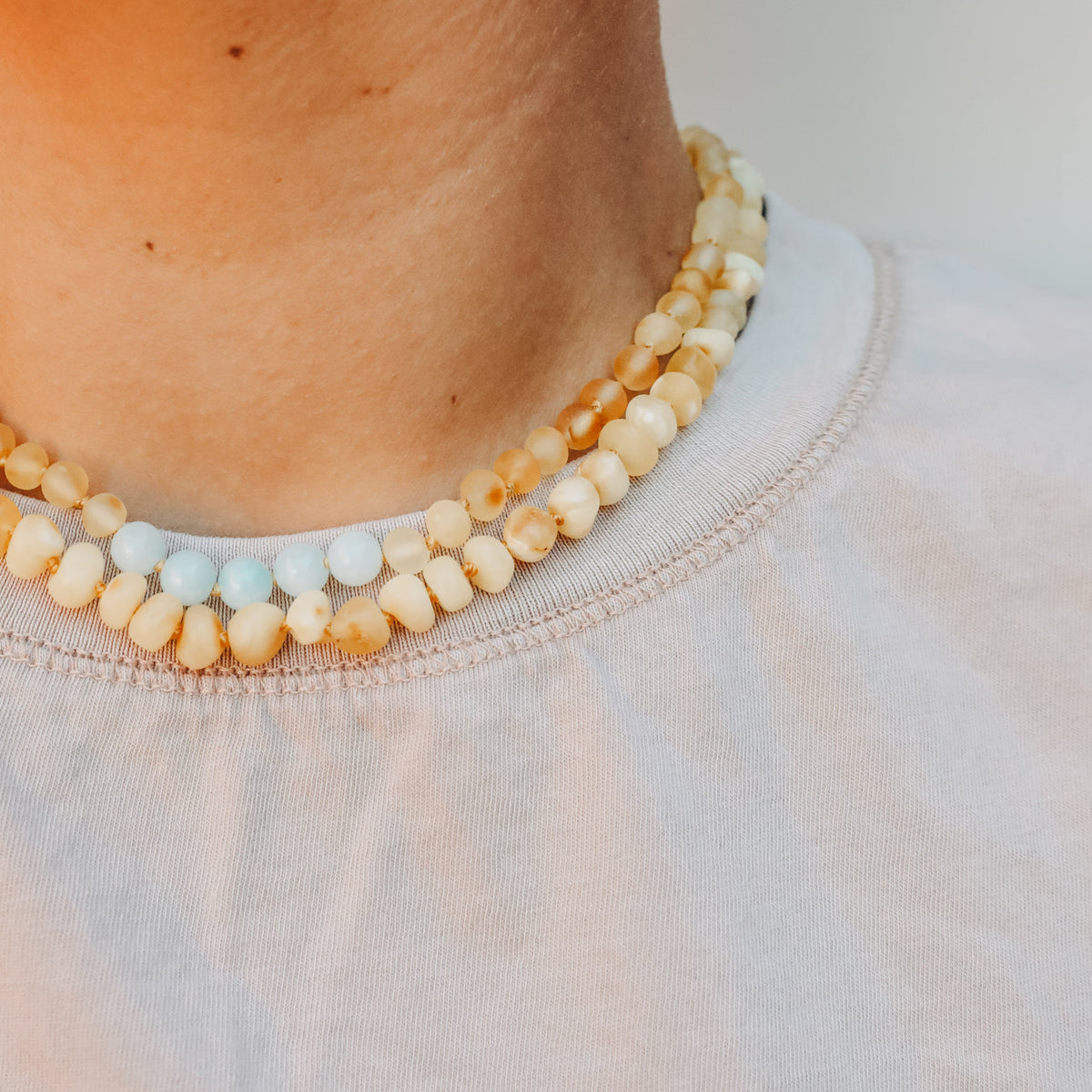 Beaded amber, white, and light blue necklace with gold-toned clasp on neckline