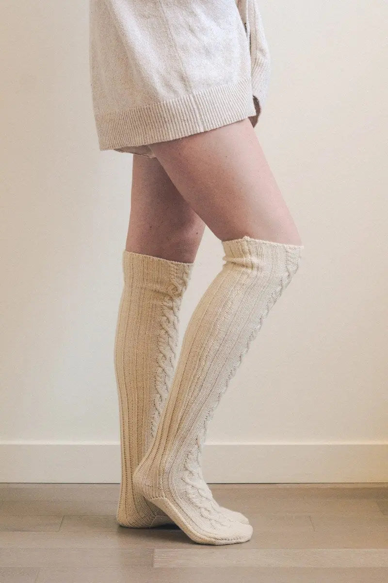 Ivory knee-high cable knit socks with ribbed knit texture
