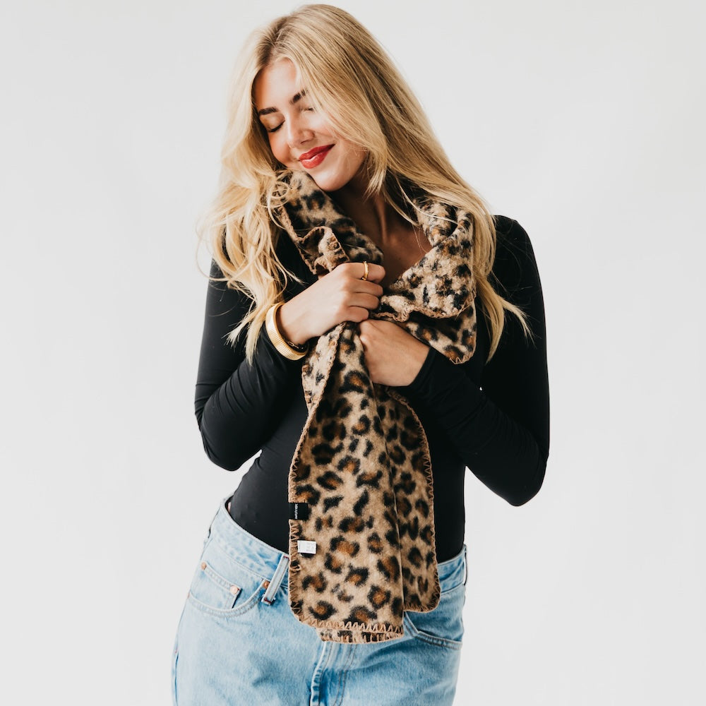 Leopard print scarf with black trim, worn as a soft loop at the neck