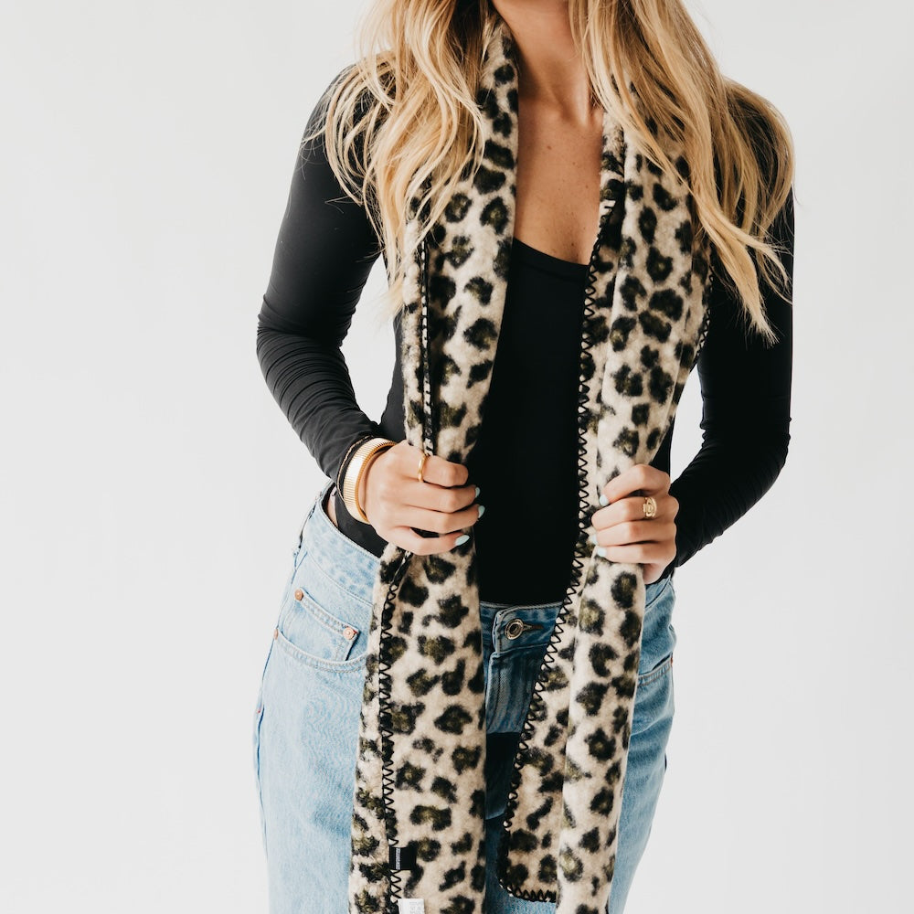 Leopard print scarf with black trim, close view of held ends