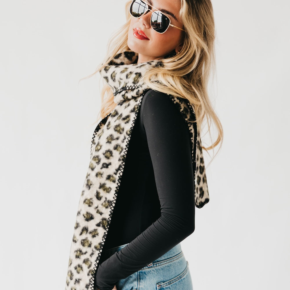 Leopard print scarf with black trim, one long side hanging and looping
