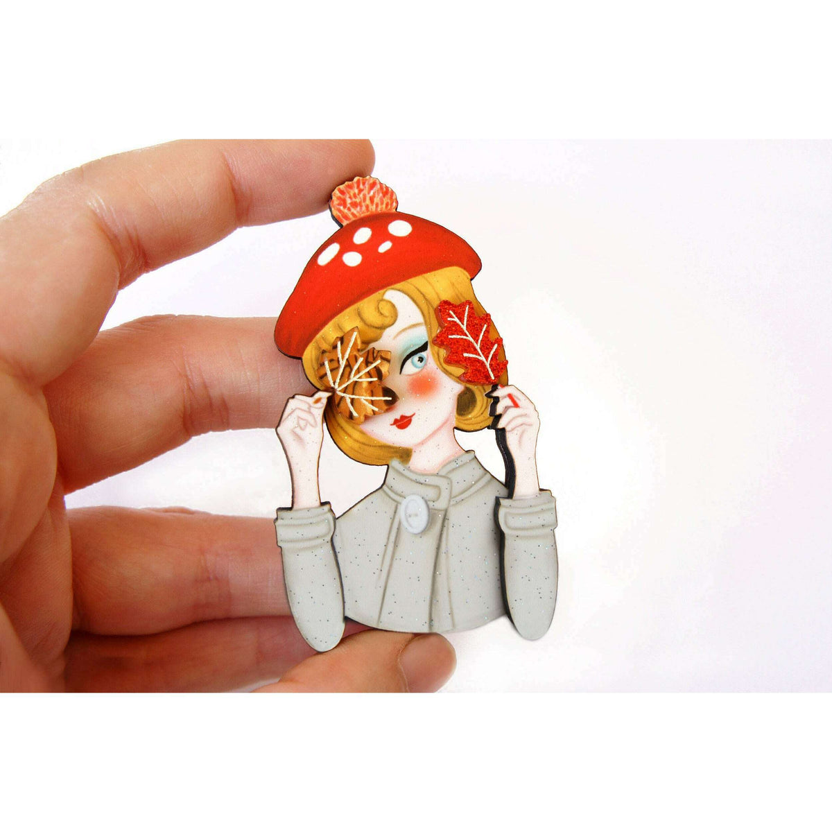 Laliblue autumn girl brooch held by hand, red mushroom hat and leaf details