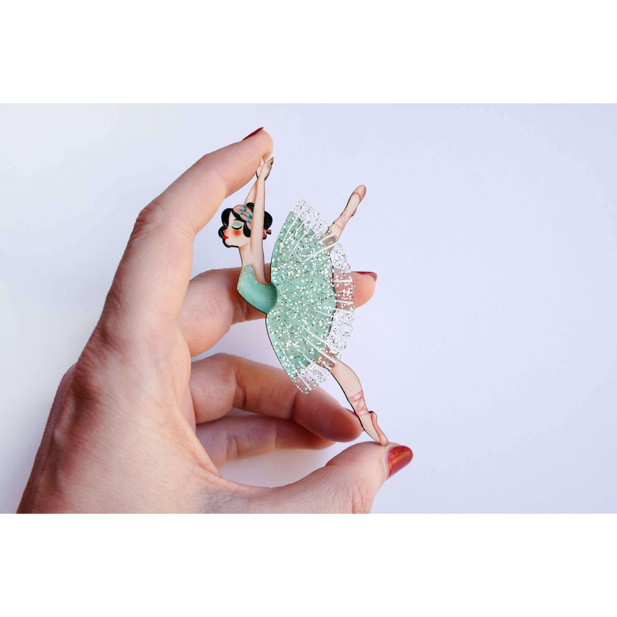 Ballet dancer brooch held in hand, teal-green glitter tutu with silver tulle fringe