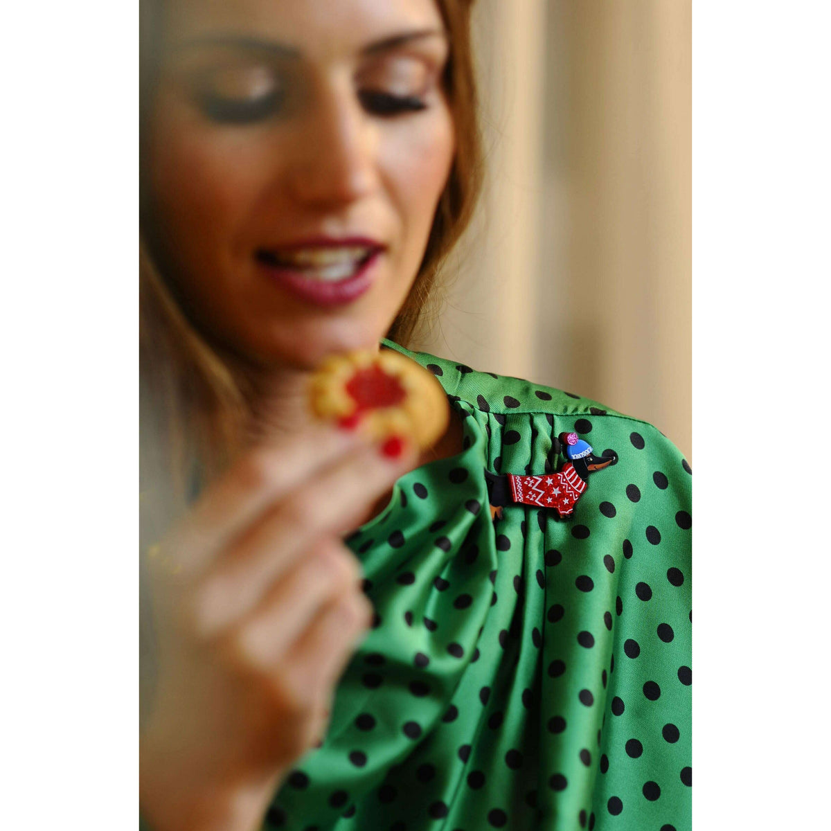 Dachshund dog brooch on green polka-dot blouse, red star sweater and blue cap