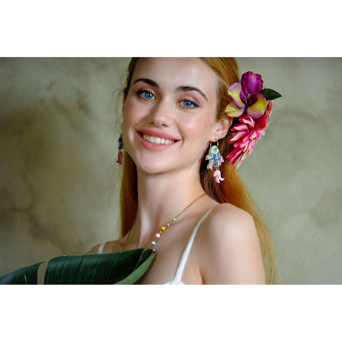 Fish drop earrings on model, colorful blue and pink enamel, gold hook closure