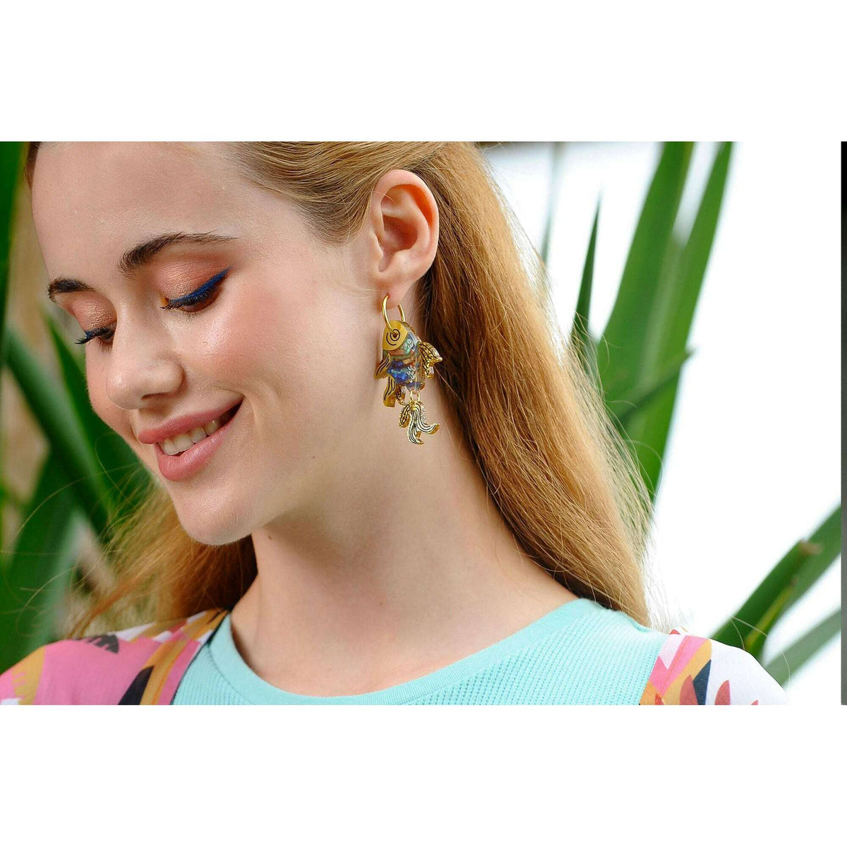 Fish enamel earrings with gold hook, blue and pink fish detail on model