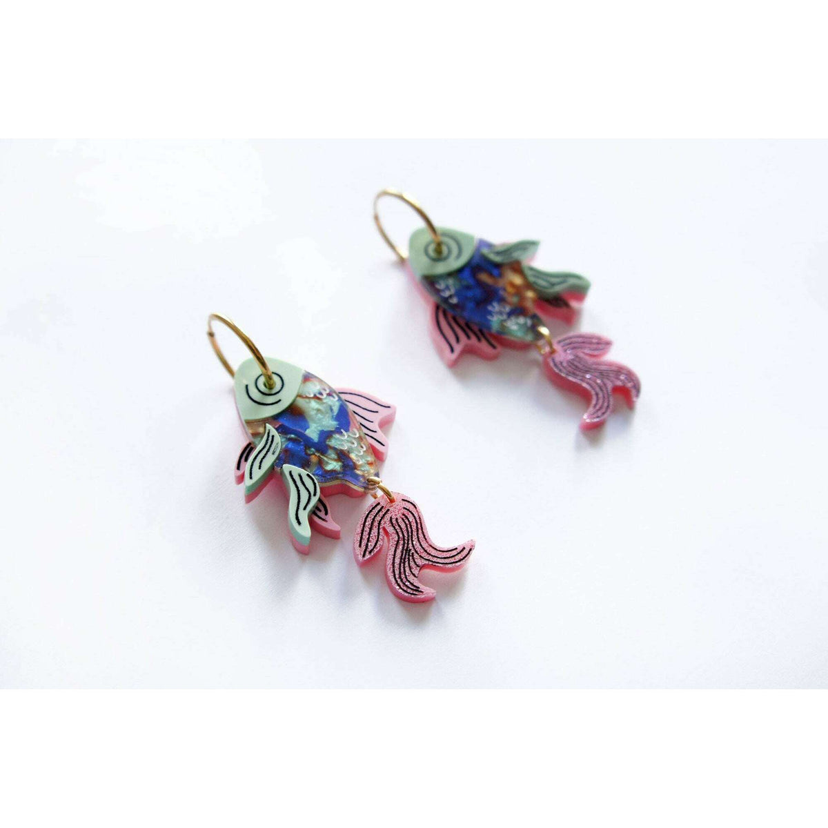 Angled view of fish drop earrings, blue and pink enamel with gold-tone hooks