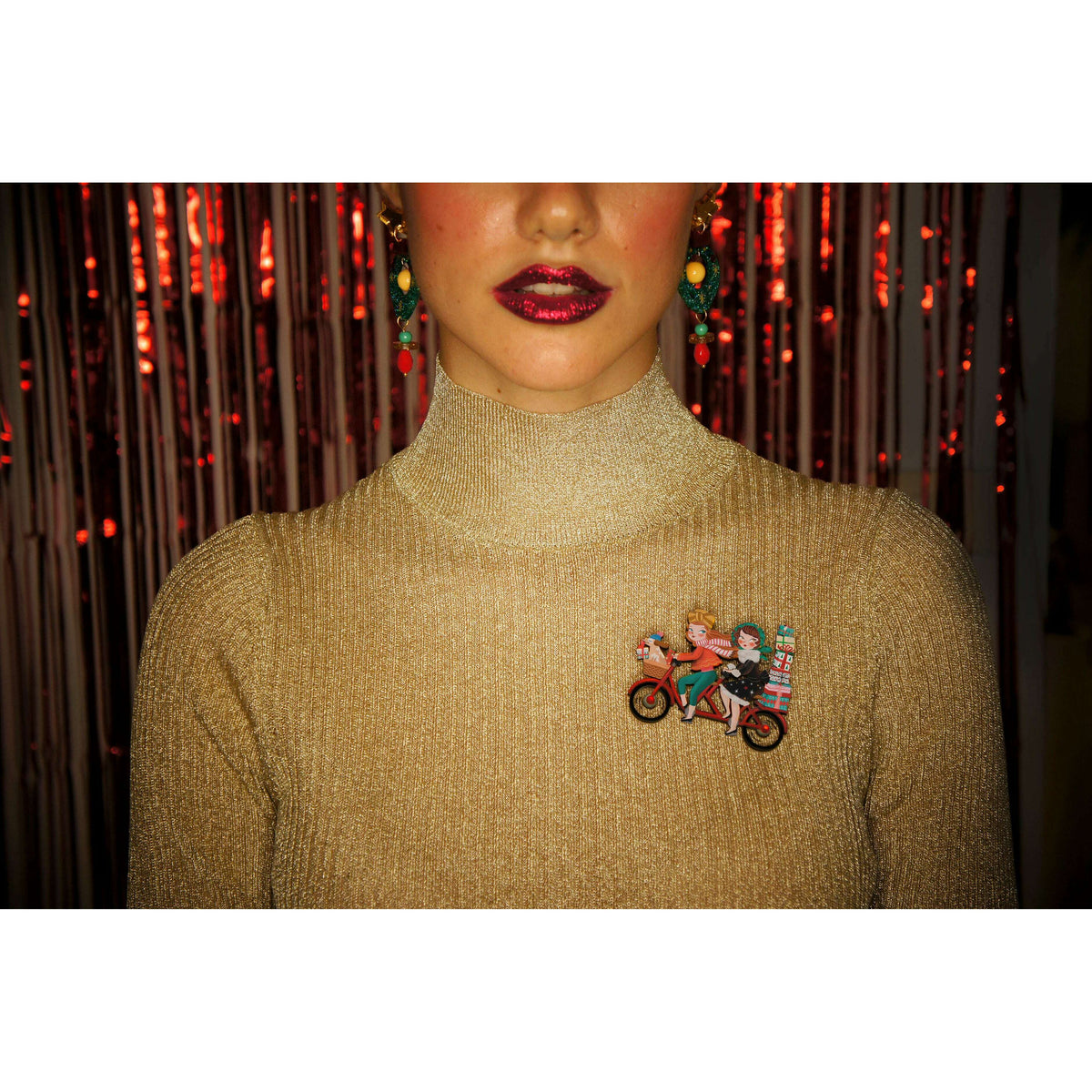 Small enamel bicycle brooch on a gold sweater, two riders with gift boxes