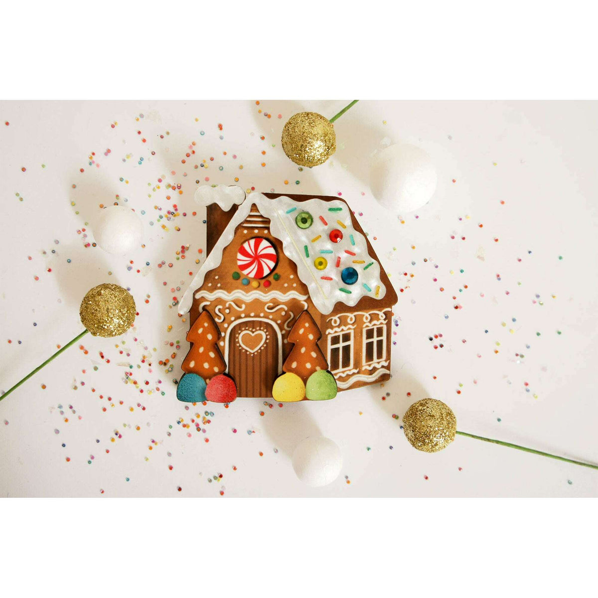 Gingerbread house enamel brooch with decorated roof, red peppermint window, and white details
