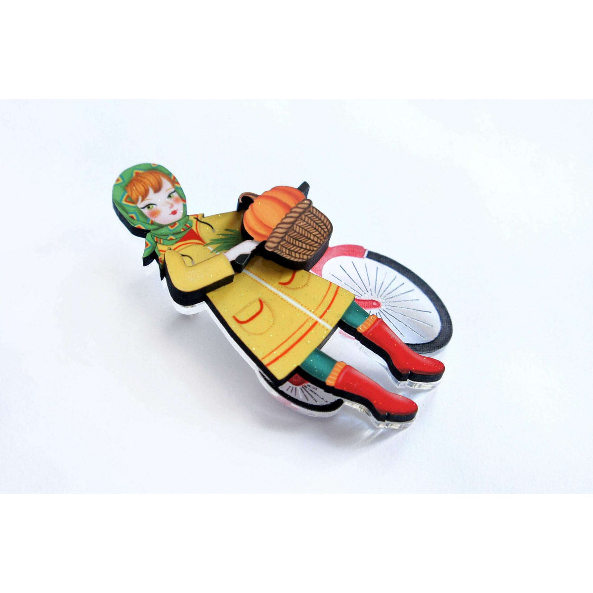 Flat bicycle girl brooch with hooded child holding basket of orange pumpkins