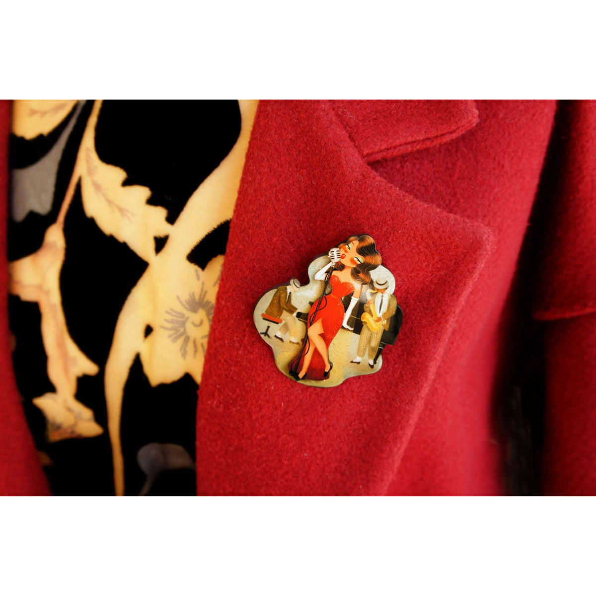 Jazz concert brooch close-up: red dress singer with microphone on speckled gold backing