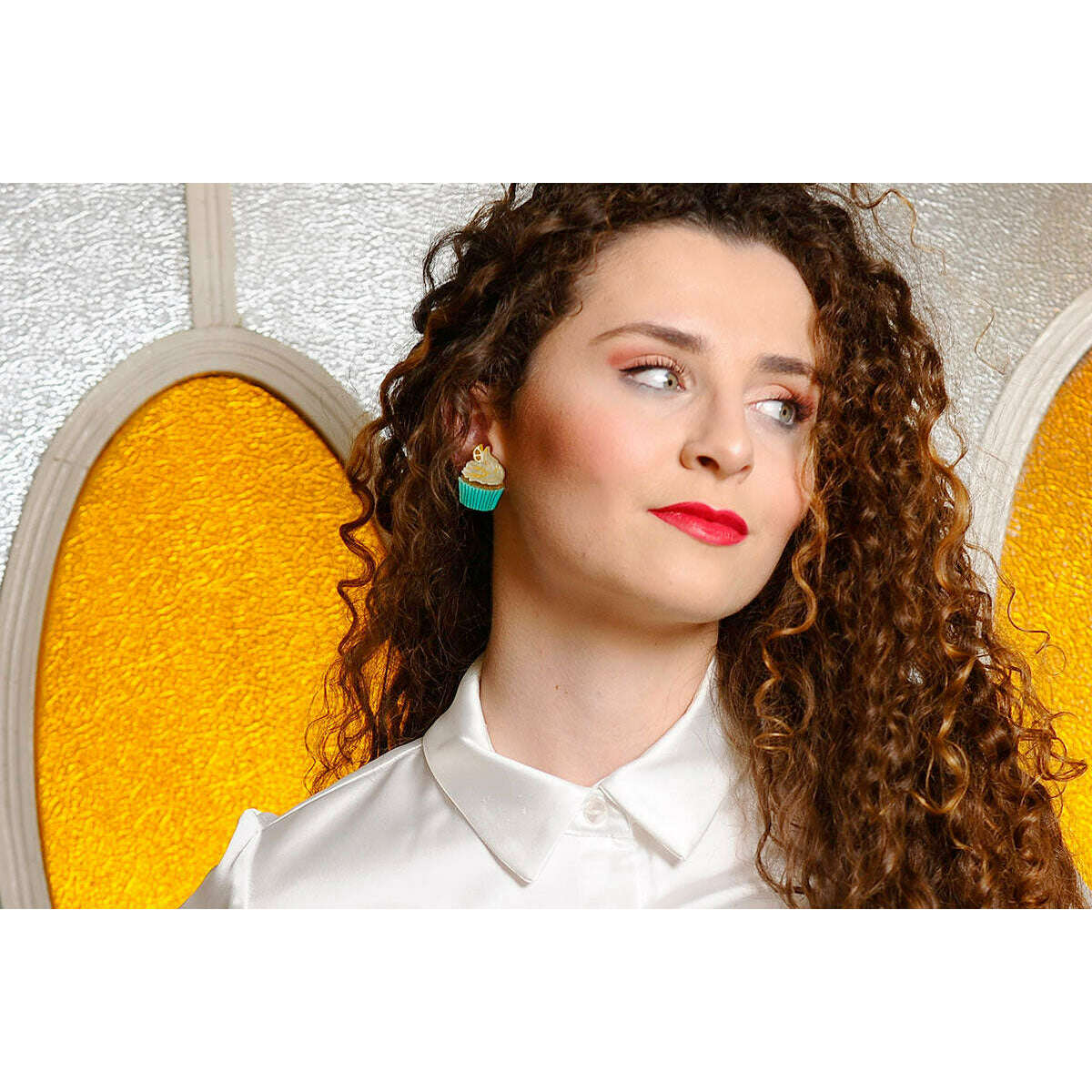 Teal muffin-shaped stud earrings with white frosting swirls and small gold accents
