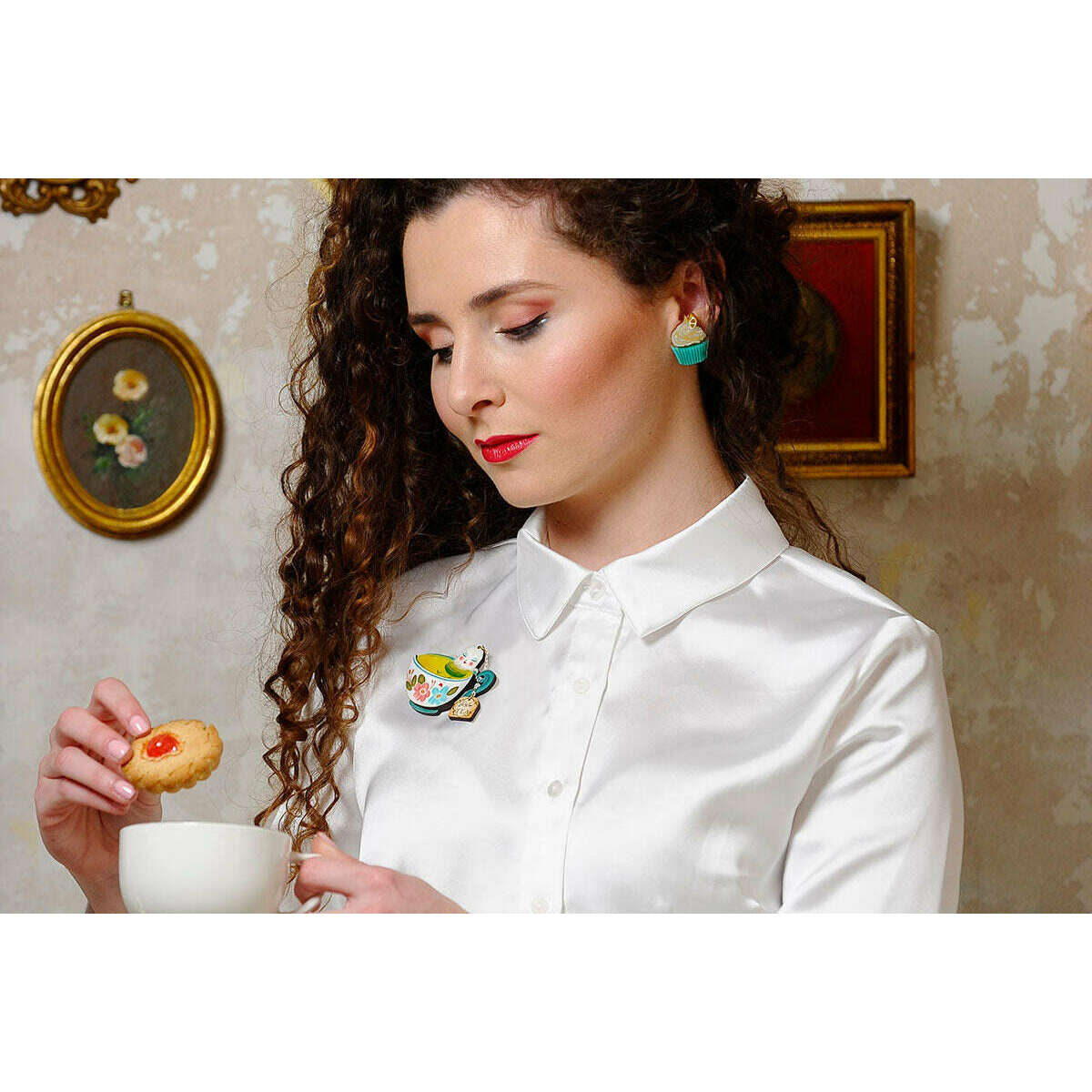 Turquoise muffin-shaped stud earrings with white frosting swirls, worn with a white shirt