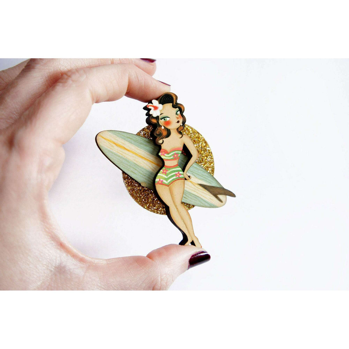 Surfer girl enamel brooch held in hand, glitter gold oval with colorful figure