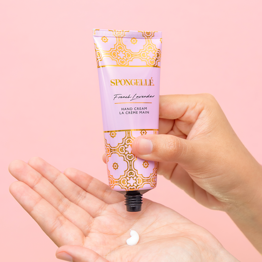 SPONGELLE French lavender hand cream tube with white cream on open palm.