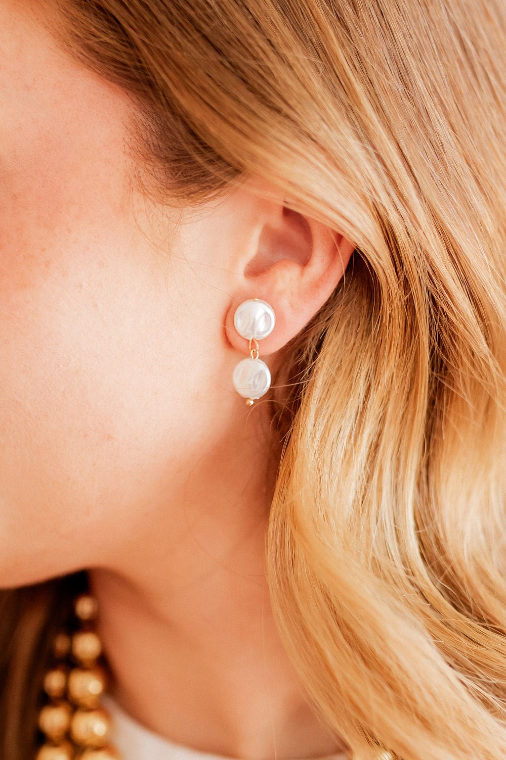Close-up of pearl drop statement earrings with gold hooks and three white pearls