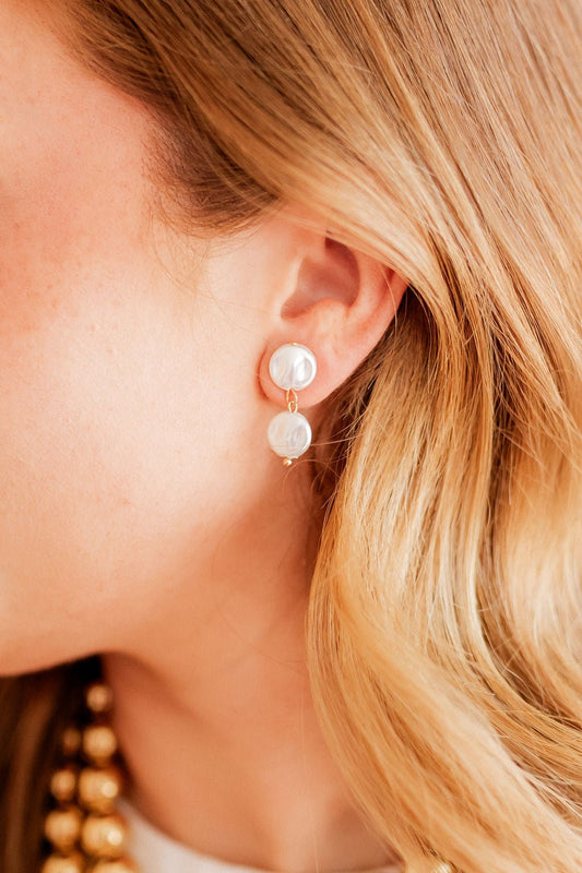 Close-up of pearl drop statement earrings with gold hooks and three white pearls
