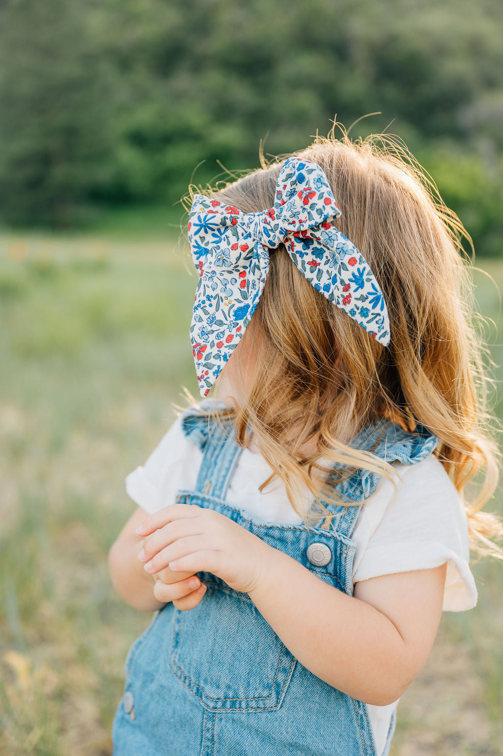 Floral hair bow on long hair, cream with blue and red flower pattern