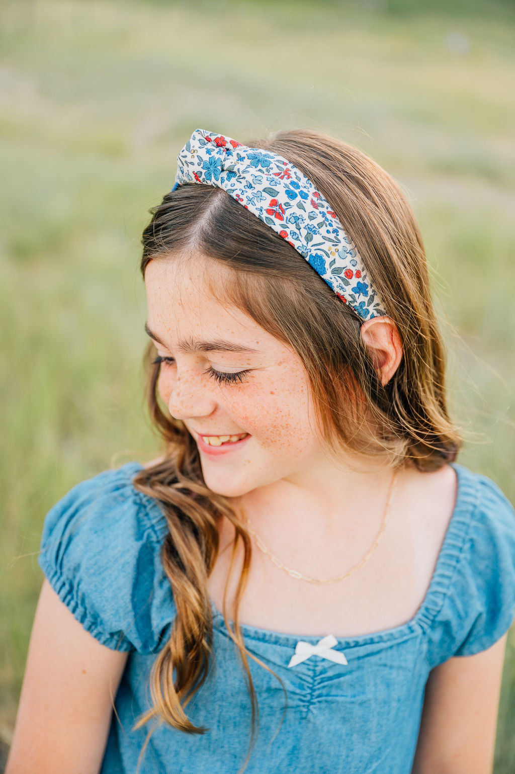 Floral knotted headband in cream with blue and red blossoms, worn by model